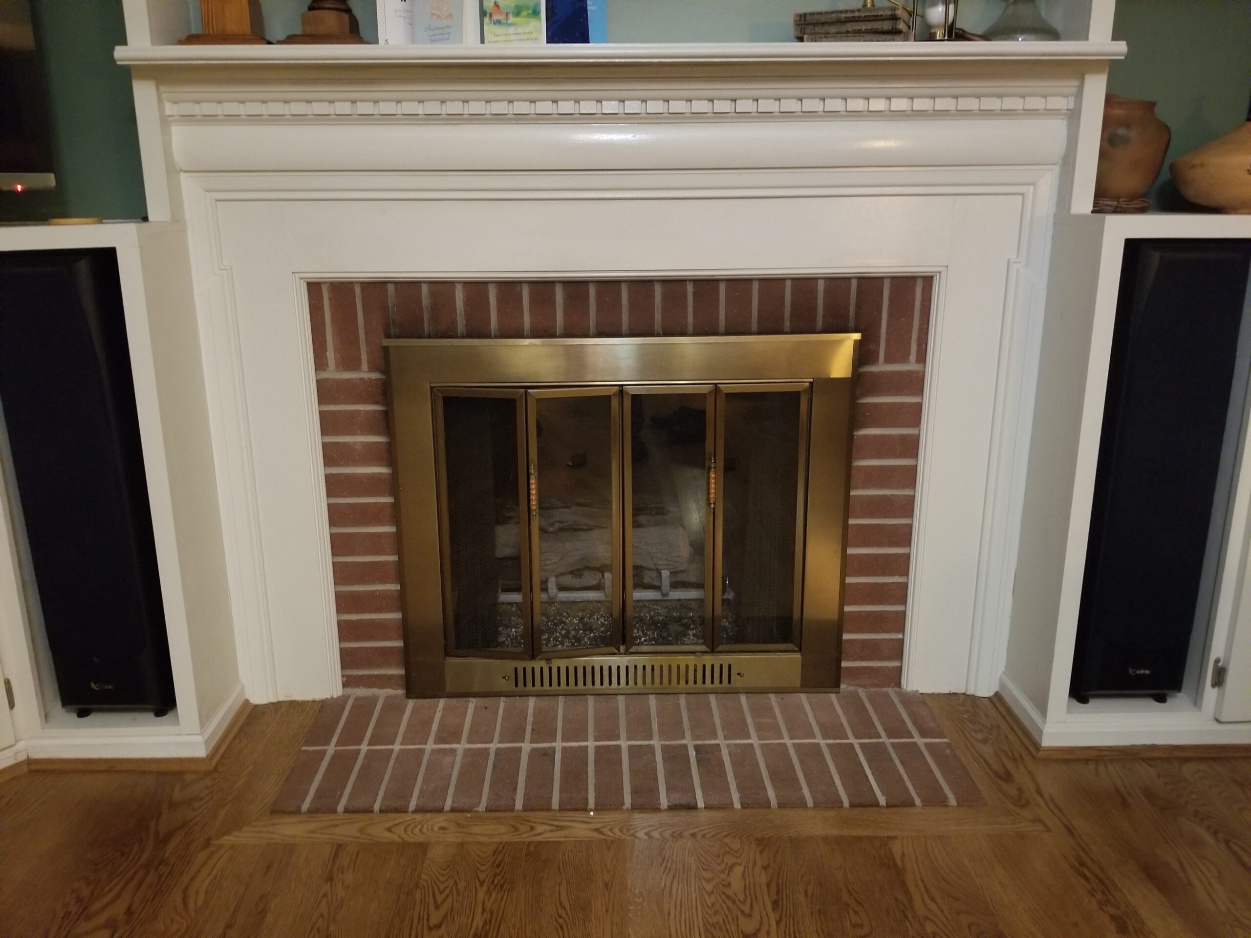 Fireplace with brass-trimmed glass doors, red brick surround, and white mantel.