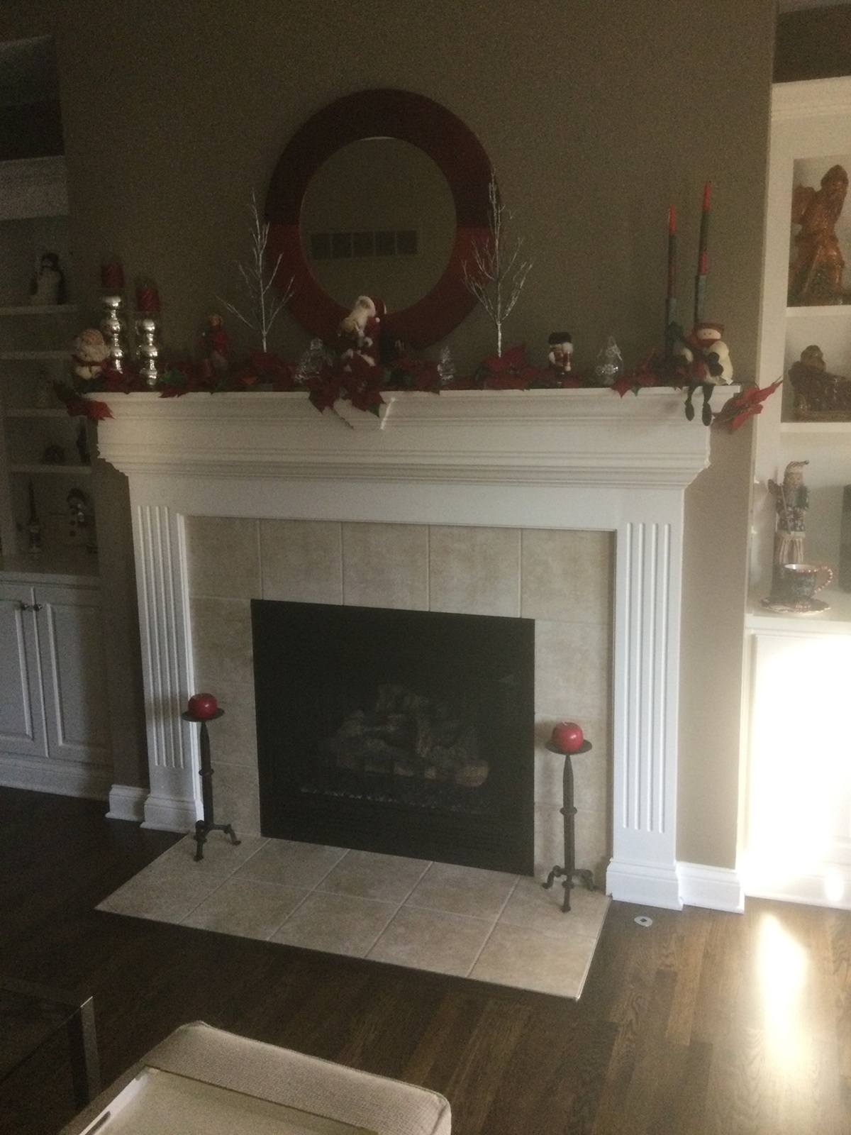 Fireplace with beige tile surround, white mantel, and holiday decorations above.