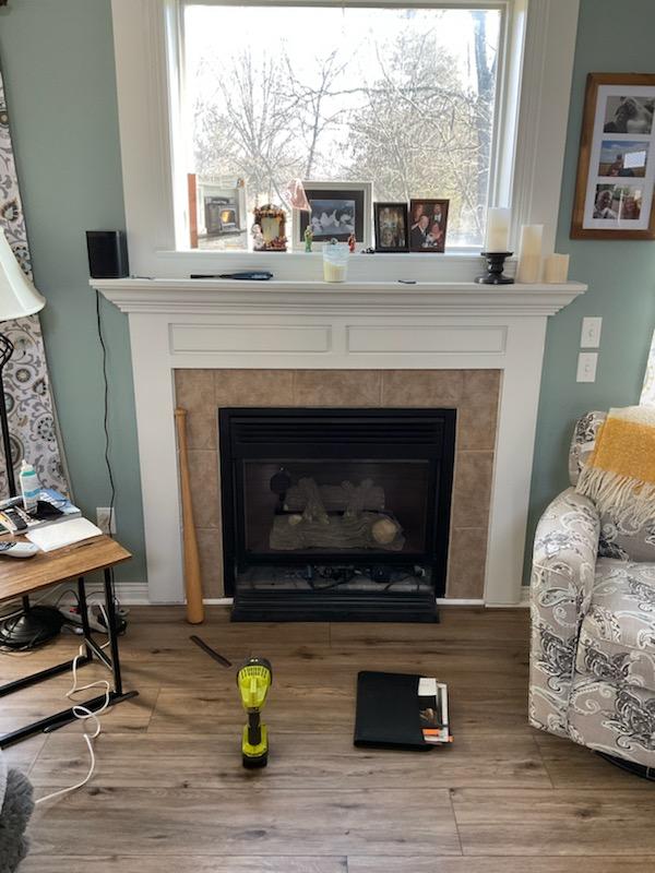 Fireplace with beige tile surround and white mantel, decorated with framed photos.