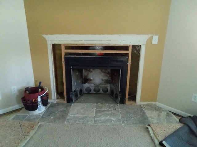 Partially dismantled fireplace with white mantel frame and exposed interior.