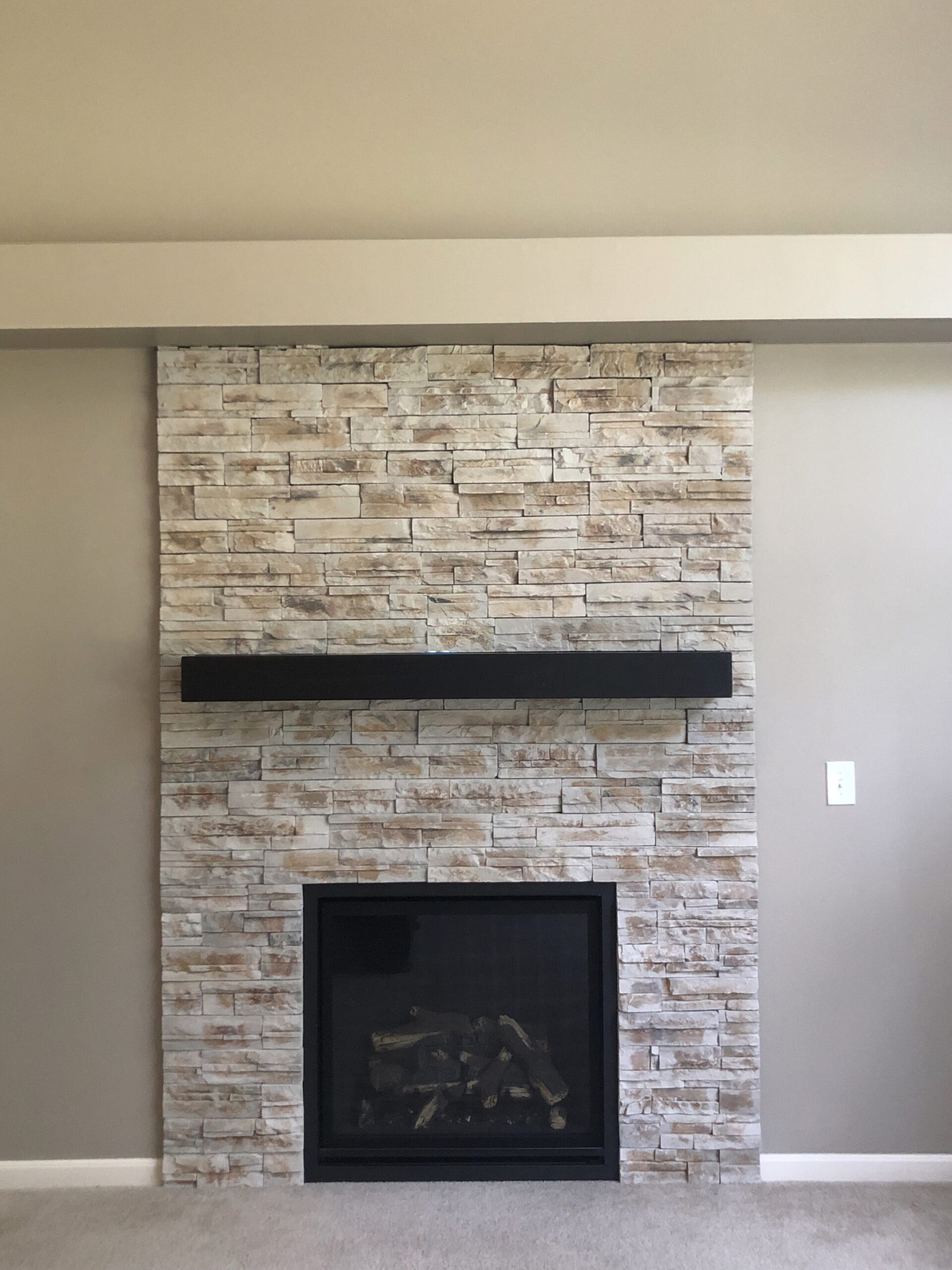 Whitewashed brick fireplace with black mantel and black firebox insert.