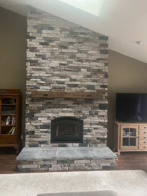 Floor-to-ceiling stone fireplace with rustic wood mantel and black wood-burning insert.